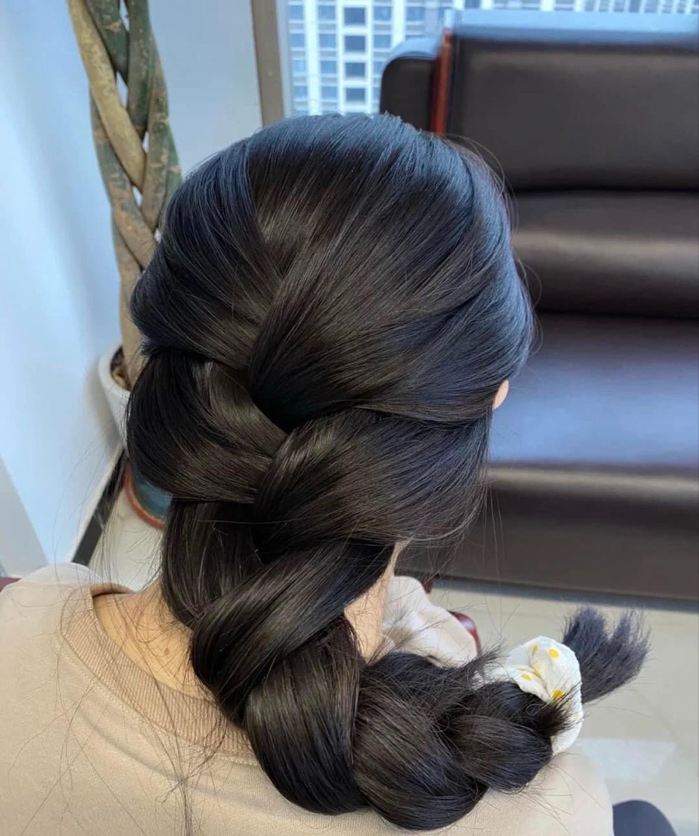 Person with braided hair in a room with a couch and plant