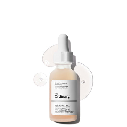 Product image of The Ordinary Lactic Acid 5% + HA exfoliating serum in a frosted glass dropper bottle. The serum is displayed against a clean white background with translucent serum drops, highlighting its lightweight texture. Formulated with lactic acid and hyaluronic acid to gently exfoliate, smooth skin texture, and support hydration.