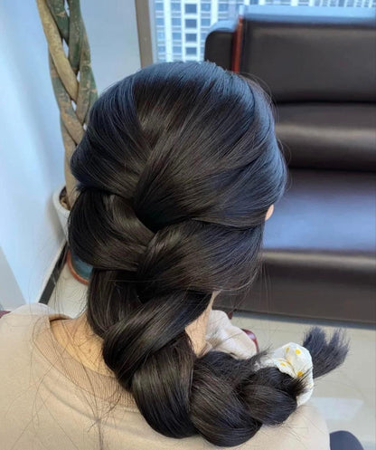 Person with braided hair in a room with a couch and plant