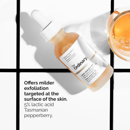 Lifestyle product image of The Ordinary Lactic Acid 5% + HA serum displayed beside a bowl of golden liquid. The graphic highlights gentle surface-level exfoliation with 5% lactic acid and Tasmanian pepperberry to help smooth skin texture, improve radiance, and reduce the appearance of dull, uneven skin while remaining suitable for sensitive skin types.