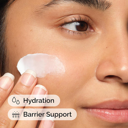 Close-up of a woman applying The Ordinary Natural Moisturizing Factors + Hyaluronic Acid moisturizer to her cheek. The image highlights key benefits including deep hydration and skin barrier support. Lightweight moisturizing cream helps strengthen the skin's natural barrier, lock in moisture, and keep skin soft, smooth, and healthy-looking throughout the day.