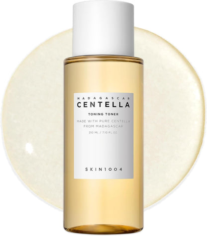 Front view of SKIN1004 Madagascar Centella Toning Toner 210ml bottle displayed against a toner texture backdrop. This hydrating Korean toner is enriched with Madagascar Centella Asiatica Extract, Hyaluronic Acid, and PHA to gently exfoliate, soothe irritation, improve skin texture, and maintain long-lasting moisture. Suitable for sensitive, dry, oily, and combination skin types.