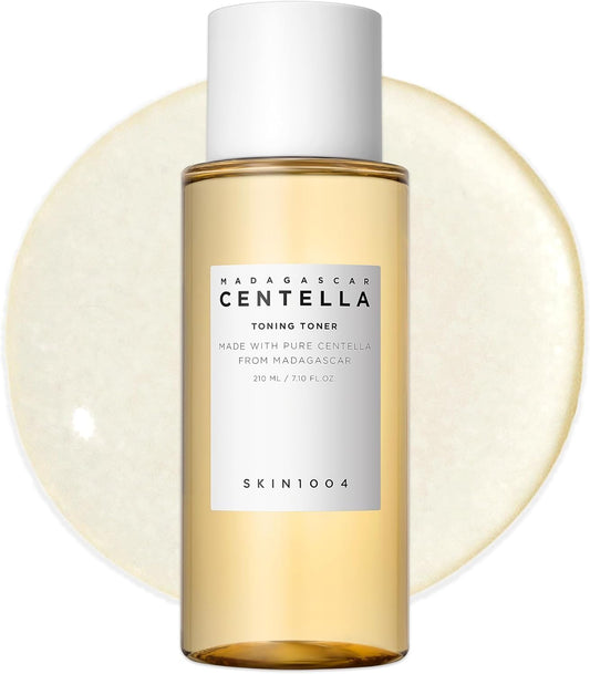 Front view of SKIN1004 Madagascar Centella Toning Toner 210ml bottle displayed against a toner texture backdrop. This hydrating Korean toner is enriched with Madagascar Centella Asiatica Extract, Hyaluronic Acid, and PHA to gently exfoliate, soothe irritation, improve skin texture, and maintain long-lasting moisture. Suitable for sensitive, dry, oily, and combination skin types.