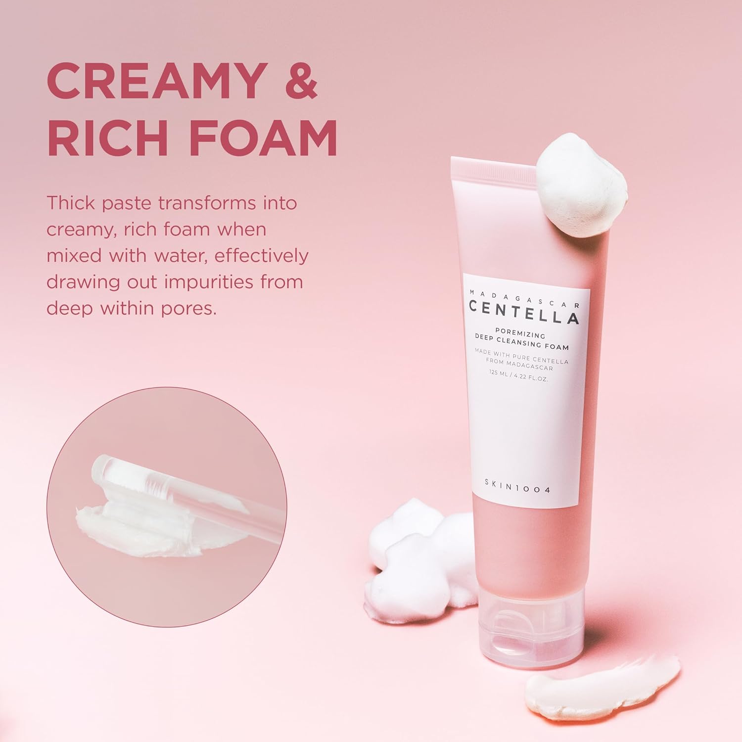 Promotional image of SKIN1004 Madagascar Centella Poremizing Deep Cleansing Foam showcasing its creamy and rich foam texture. The pink cleanser tube is displayed with soft foam accents, highlighting how the thick paste transforms into a dense, creamy lather when mixed with water. Designed to help draw out impurities from deep within pores while providing a thorough yet gentle cleanse.