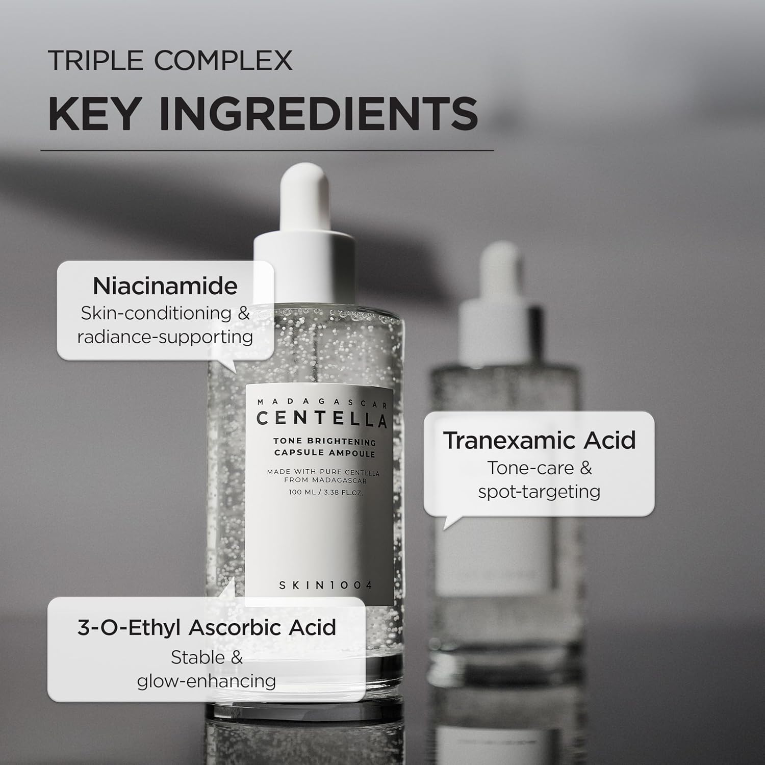 Informational image showcasing the key ingredients in SKIN1004 Madagascar Centella Tone Brightening Capsule Ampoule 100ml. Highlights Niacinamide for skin conditioning and radiance support, Tranexamic Acid for tone care and spot-targeting, and 3-O-Ethyl Ascorbic Acid for stable brightening and glow enhancement. Features the ampoule bottle with visible brightening capsules on a minimalist gray background.