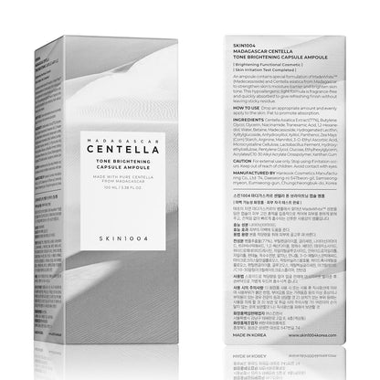 Front and back view of SKIN1004 Madagascar Centella Tone Brightening Capsule Ampoule 100ml retail packaging. The box features a minimalist white desert-inspired design and includes product information, ingredients, usage instructions, and brightening benefits powered by Centella Asiatica, Niacinamide, Tranexamic Acid, and MadeWhite™ technology.