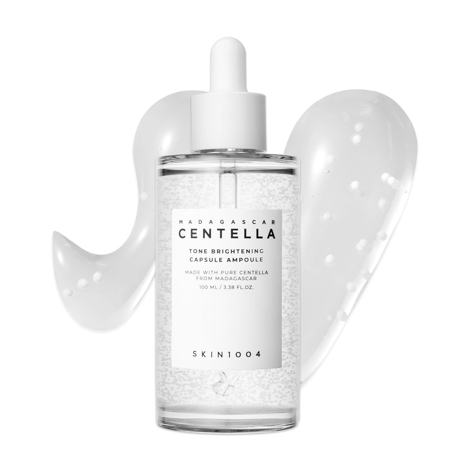 SKIN1004 Madagascar Centella Tone Brightening Capsule Ampoule 100ml serum bottle with dropper applicator. Features brightening capsule technology suspended in a lightweight hydrating formula designed to improve uneven skin tone, enhance radiance, and provide soothing care with Centella Asiatica. Displayed against a clean white background with serum texture swatches.