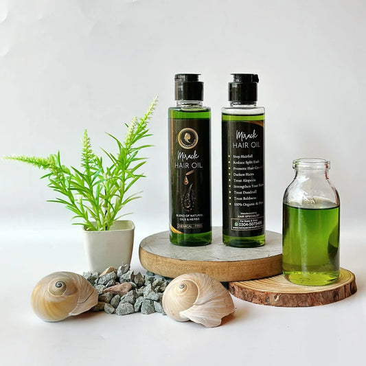 Two bottles of hair oil on a wooden stand with a plant and shells on a white background